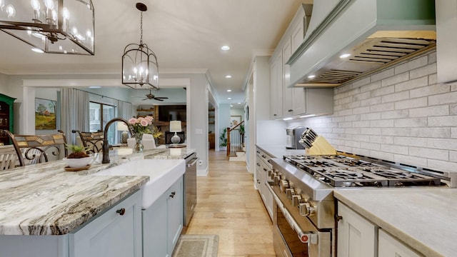 kitchen featuring premium range hood, appliances with stainless steel finishes, ceiling fan with notable chandelier, and white cabinetry