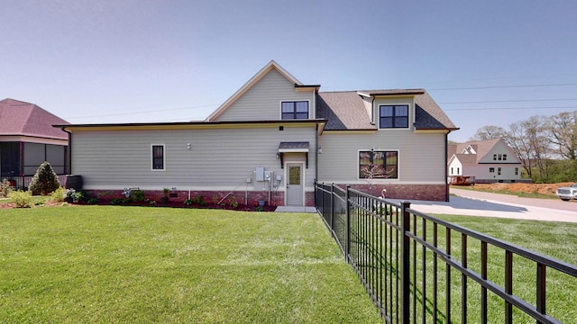 rear view of house with fence and a lawn
