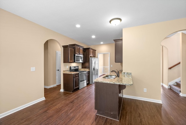 1313 Allmon Dr, Clarksville, TN 37042 - kitchen with stainless steel appliances, a sink, dark brown cabinets, a kitchen breakfast bar, and arched walkways