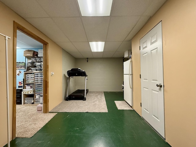 exercise room with tile patterned floors, concrete block wall, and a drop ceiling
