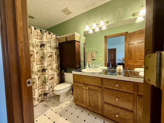 bathroom featuring a textured ceiling, vanity, visible vents, toilet, and tile patterned floors