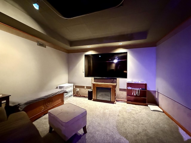 home theater featuring baseboards, a raised ceiling, carpet, and a fireplace