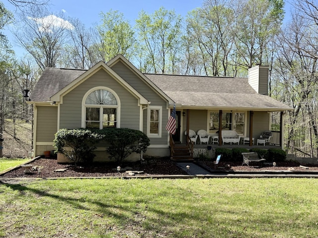ranch-style home with roof with shingles, a chimney, covered porch, and a front yard