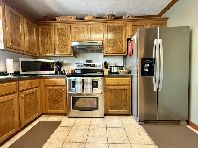 kitchen with brown cabinetry, decorative backsplash, under cabinet range hood, and stainless steel appliances