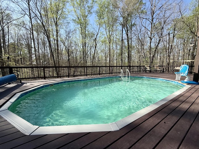 view of swimming pool with a fenced in pool and a deck