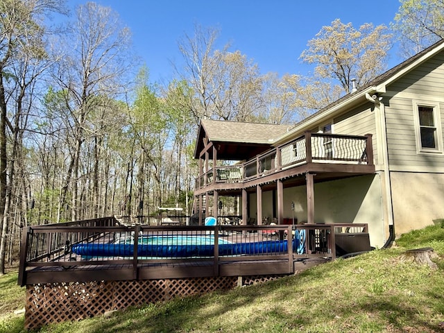 back of house with a wooden deck, a fenced in pool, and a lawn