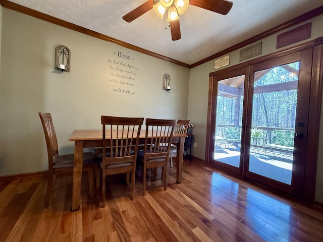 dining area with ornamental molding, wood finished floors, and a textured ceiling