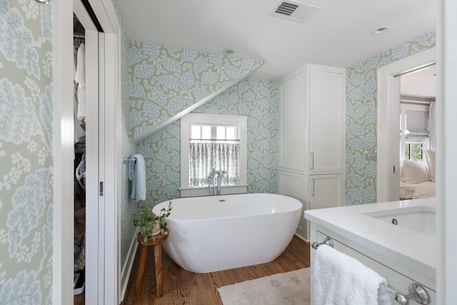 4610 Elkins Ave, Nashville, TN 37209 - bathroom featuring wallpapered walls, wood finished floors, a freestanding tub, vanity, and a closet