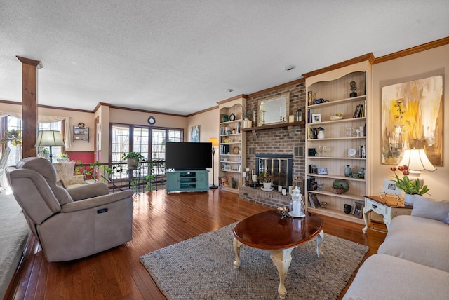 living area featuring ornamental molding, wood-type flooring, a brick fireplace, and a textured ceiling