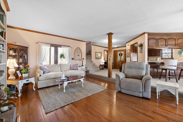 living room with stairs, ornate columns, hardwood / wood-style floors, and ornamental molding