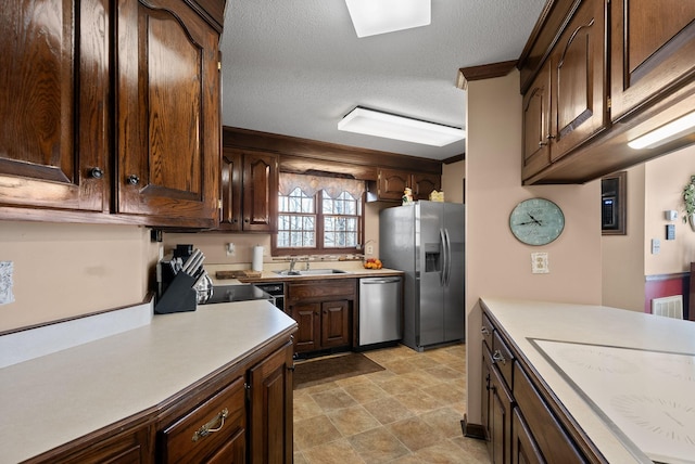 kitchen featuring a sink, light countertops, appliances with stainless steel finishes, dark brown cabinetry, and a textured ceiling