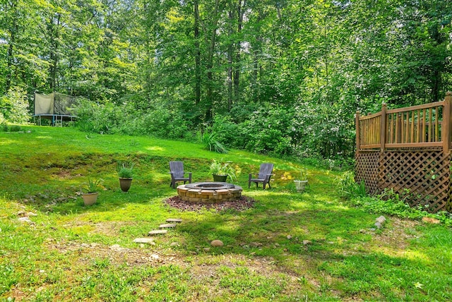 4862 Louise Rd, Cumberland Furnace, TN 37051 - view of green lawn featuring a fire pit, a trampoline, and a wooden deck