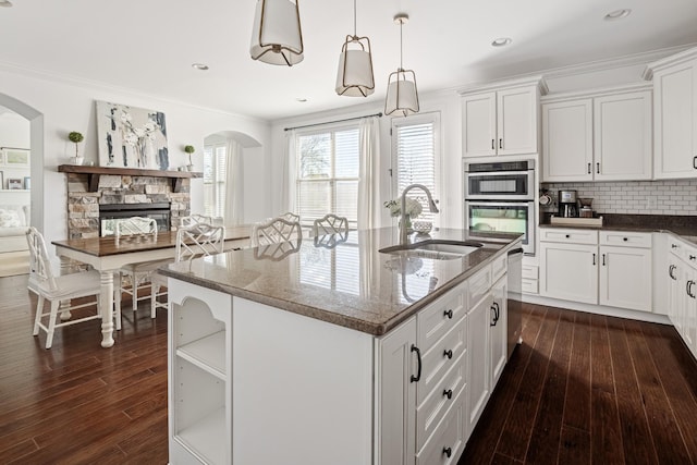 kitchen with tasteful backsplash, a sink, ornamental molding, appliances with stainless steel finishes, and dark wood-style floors
