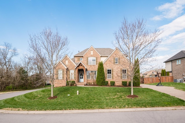 traditional-style home featuring fence, stone siding, a front lawn, and brick siding