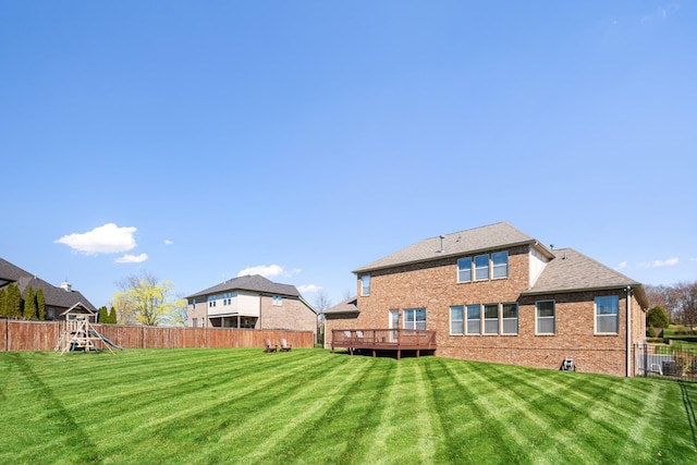 back of house with a lawn, a fenced backyard, a wooden deck, and brick siding