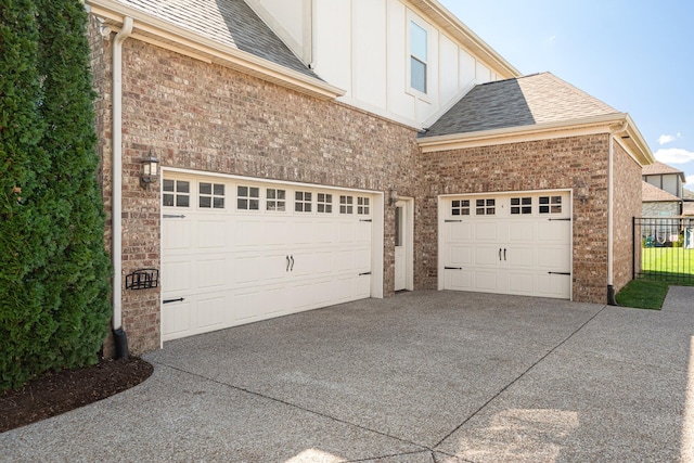 garage with concrete driveway and fence
