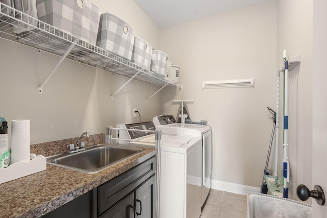 laundry area with light tile patterned floors, washing machine and dryer, baseboards, and a sink