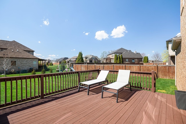 deck featuring a yard, a fenced backyard, a playground, and a residential view
