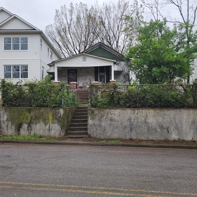 view of front of property featuring covered porch and stairway
