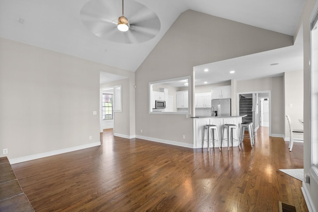 unfurnished living room with visible vents, baseboards, dark wood-style flooring, ceiling fan, and high vaulted ceiling