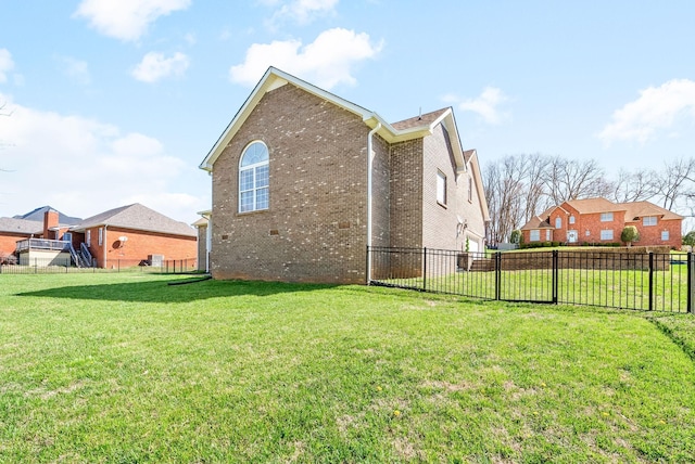 view of side of home with brick siding, fence, and a lawn