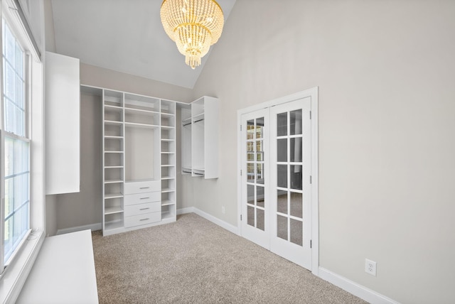 walk in closet featuring high vaulted ceiling, carpet flooring, and an inviting chandelier