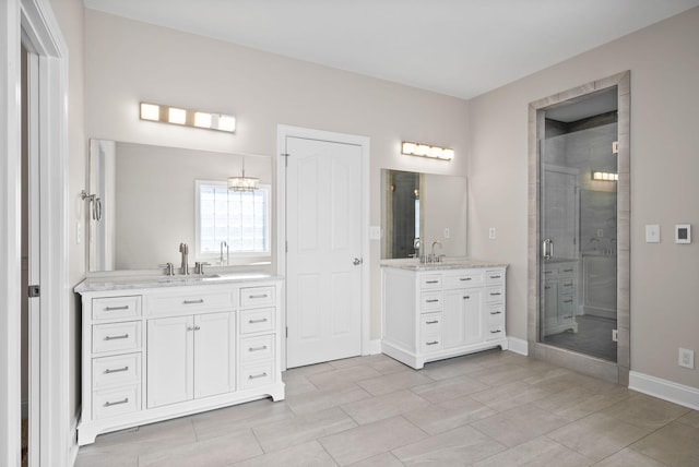 full bathroom with a stall shower, two vanities, a sink, and baseboards