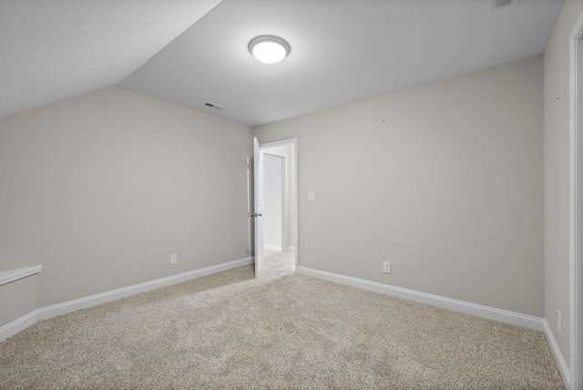 interior space with a textured ceiling, visible vents, baseboards, and vaulted ceiling