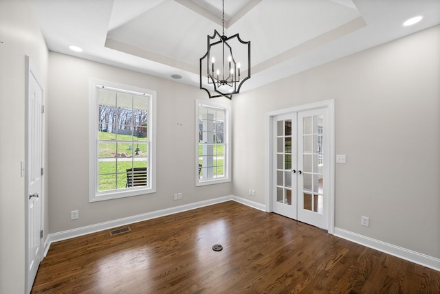 unfurnished dining area featuring a raised ceiling, dark wood-type flooring, french doors, and visible vents