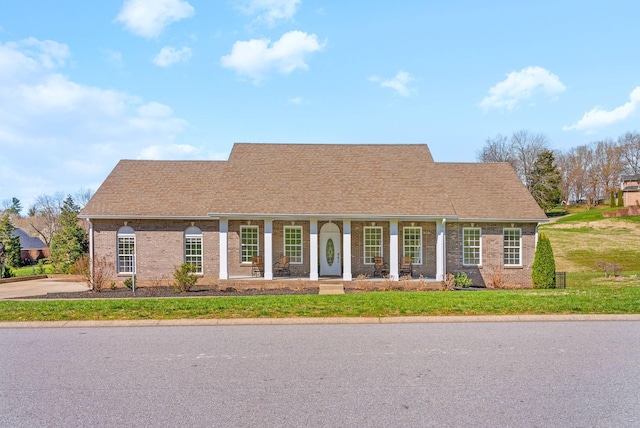 view of front facade featuring a front yard, brick siding, and covered porch