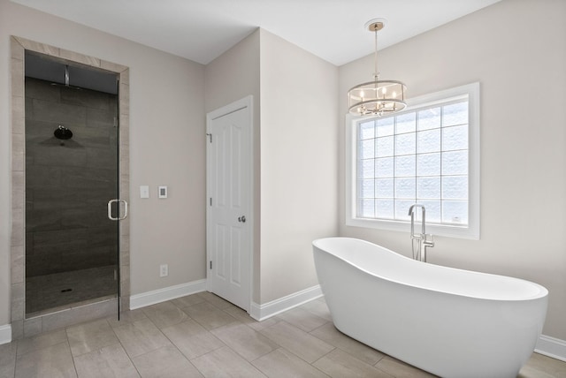 bathroom with a stall shower, a freestanding tub, a notable chandelier, and baseboards