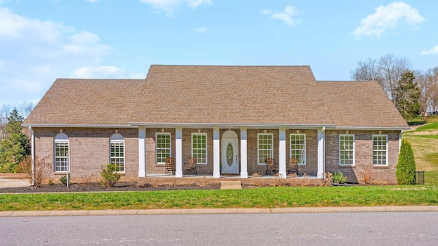 view of front of home featuring brick siding, a front yard, and covered porch