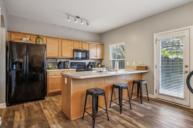 kitchen featuring black appliances, a peninsula, a sink, and light countertops