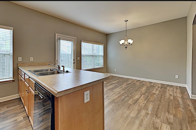 kitchen with a sink, light wood-type flooring, plenty of natural light, a notable chandelier, and black dishwasher