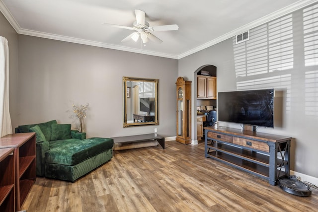 living room with visible vents, ornamental molding, arched walkways, light wood-type flooring, and ceiling fan