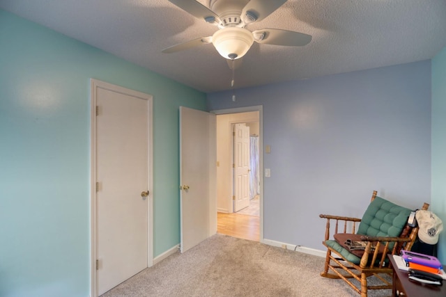 living area with carpet flooring, a textured ceiling, baseboards, and ceiling fan