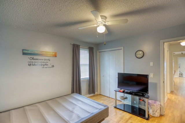 bedroom with a closet, ceiling fan, wood finished floors, and a textured ceiling