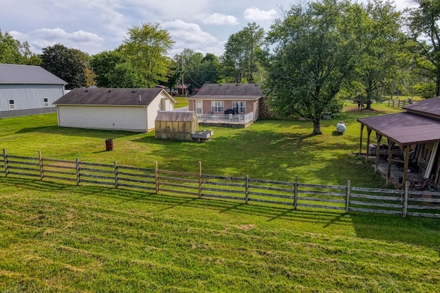 view of yard featuring a deck, a rural view, fence, and an outdoor structure