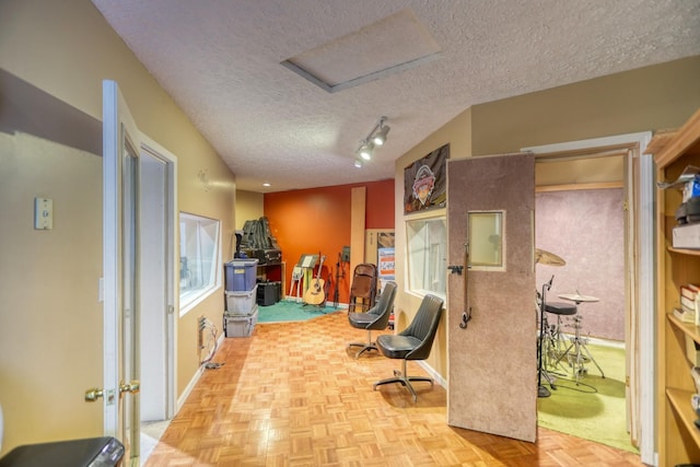 exercise area with a textured ceiling, attic access, and baseboards