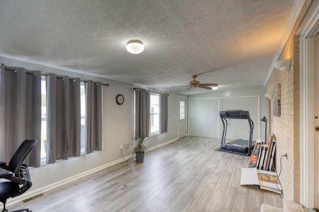 workout area featuring visible vents, baseboards, ceiling fan, a textured ceiling, and wood finished floors