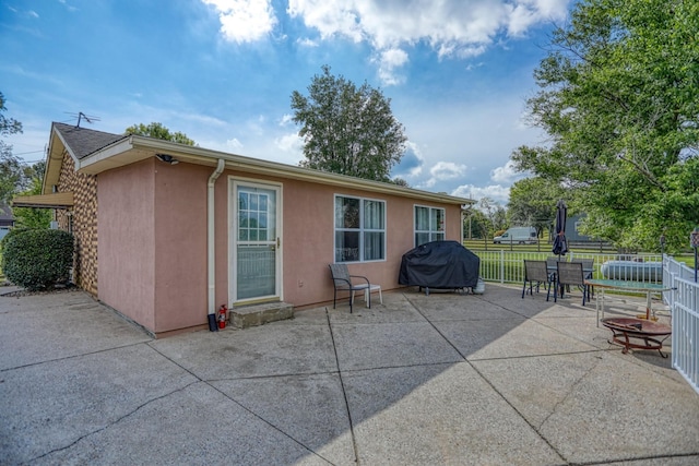 rear view of house with fence, a patio, and stucco siding