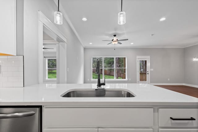 kitchen with ornamental molding, open floor plan, a ceiling fan, white cabinets, and a sink