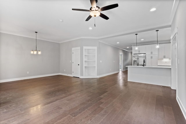 unfurnished living room featuring baseboards, ornamental molding, recessed lighting, dark wood-style floors, and ceiling fan with notable chandelier