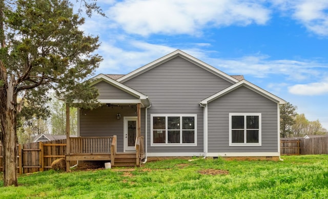 rear view of property with a yard, a deck, and fence