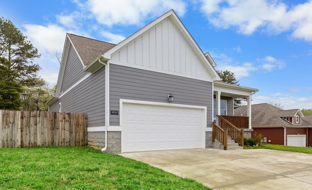 view of home's exterior with board and batten siding, a lawn, fence, a shingled roof, and concrete driveway
