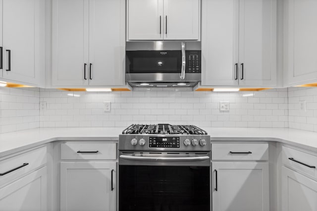 kitchen featuring tasteful backsplash, light countertops, white cabinets, and stainless steel appliances