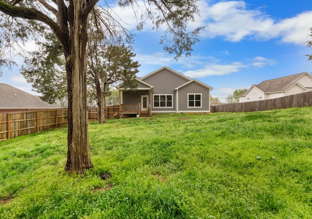 back of house with a fenced backyard, a wooden deck, and a lawn