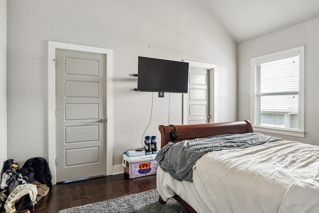 bedroom with vaulted ceiling, dark wood-style floors, and baseboards