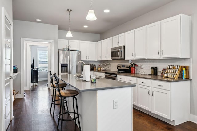 kitchen with recessed lighting, a kitchen breakfast bar, decorative light fixtures, decorative backsplash, and appliances with stainless steel finishes