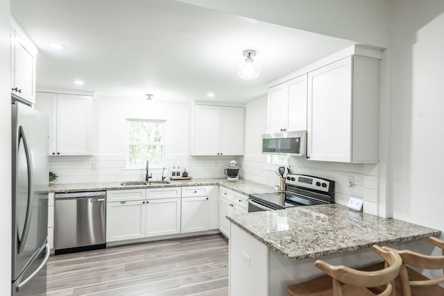 375 Mount Vernon Rd, Bethpage, TN 37022 - kitchen featuring tasteful backsplash, a peninsula, light wood-style floors, appliances with stainless steel finishes, and a sink